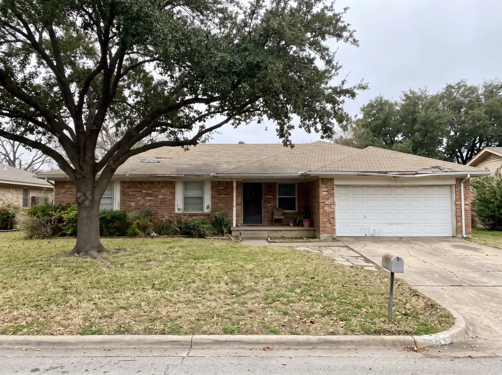 Ranch home with a worn, hail-damaged shingle roof before repair