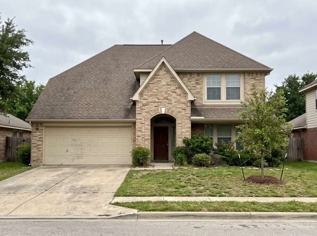 Two-story brick home with an aging gray shingle roof